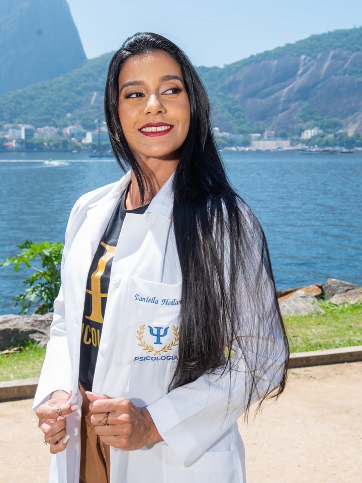 Daniella Hollanda sorrindo, olhando por cima do ombro, com o jaleco branco