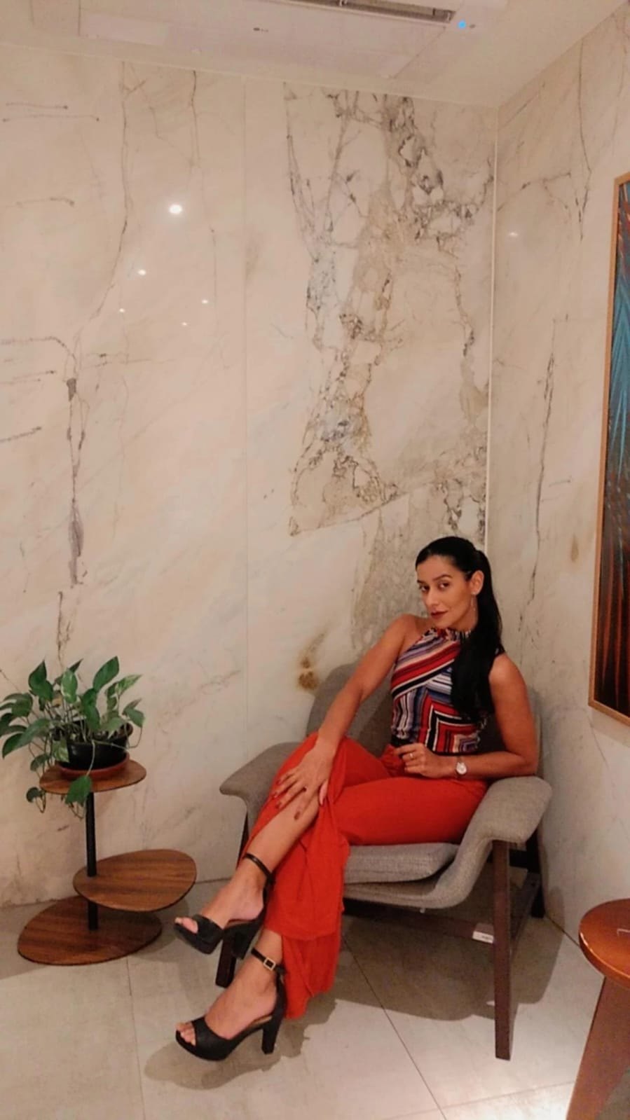 Daniella Hollanda sentada em uma poltrona, em um ambiente claro e acolhedor